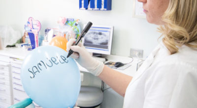 Dipendente che scrive il nome di un bambino su un palloncino, Studio Dentistico Galassini