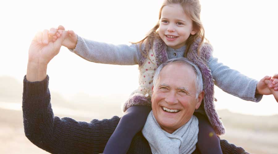 Anziano sorridente con bambina sulle spalle